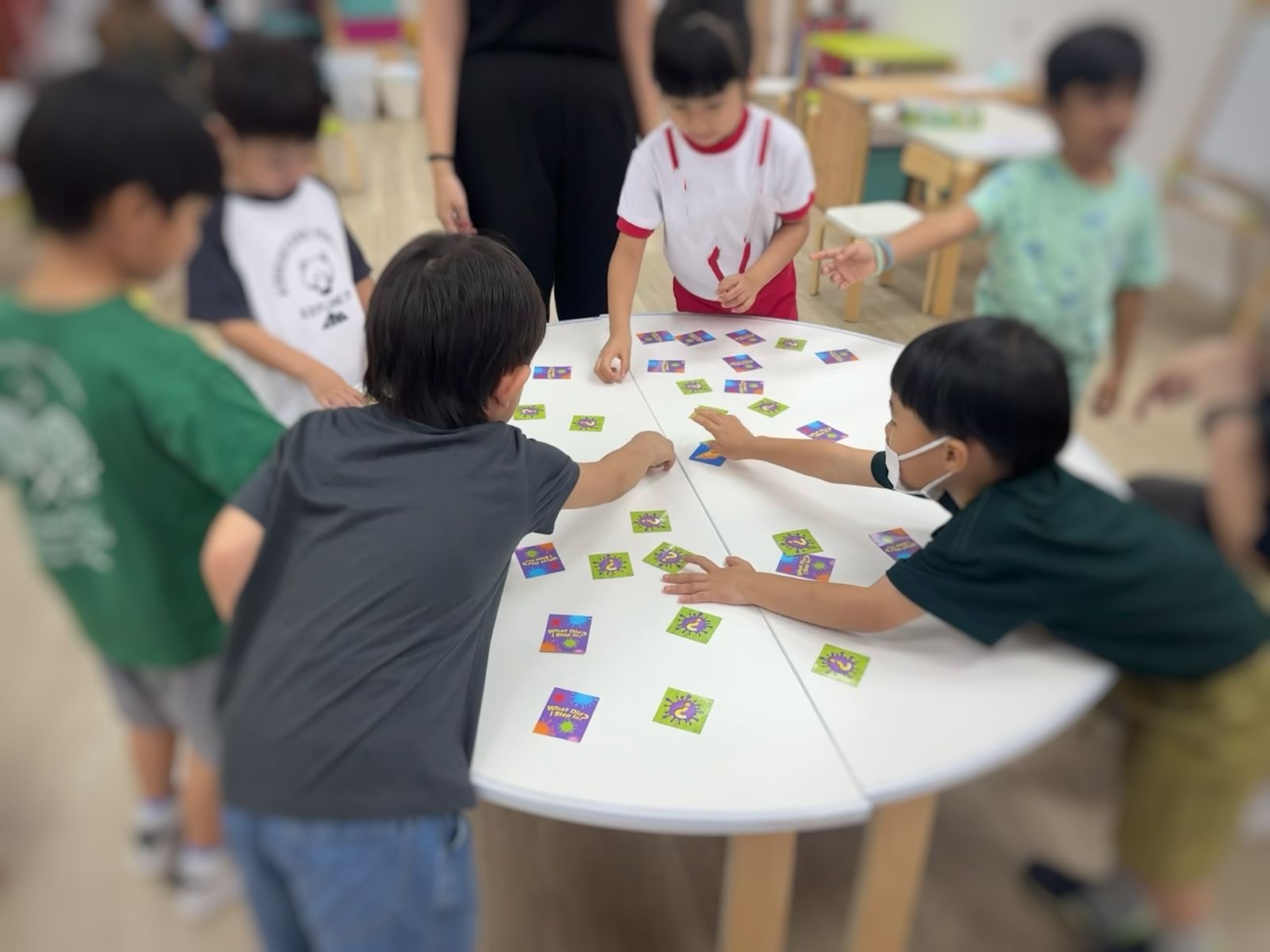 Kids engaged in a fun card game at a table, sharing laughter and excitement in a lively atmosphere.