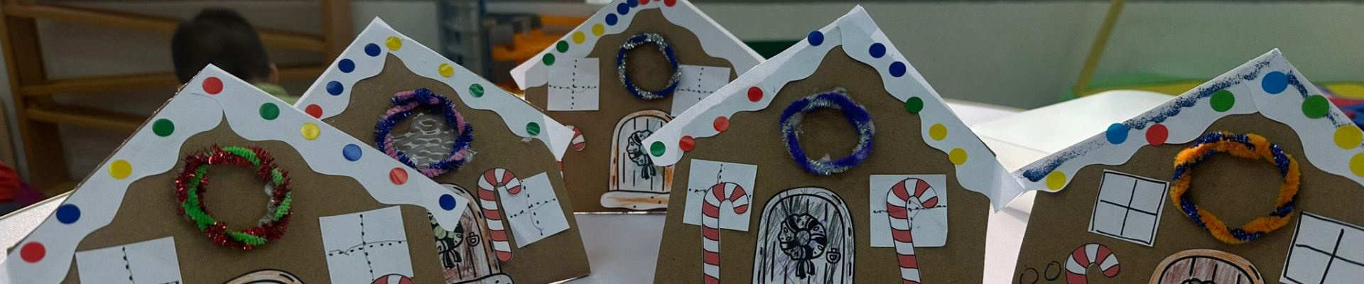 A charming display of gingerbread houses arranged on a festive table, showcasing colorful icing and candy decorations.