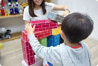 A teacher and child engaged in play, constructing a colorful brick building set, showcasing creativity and fun.