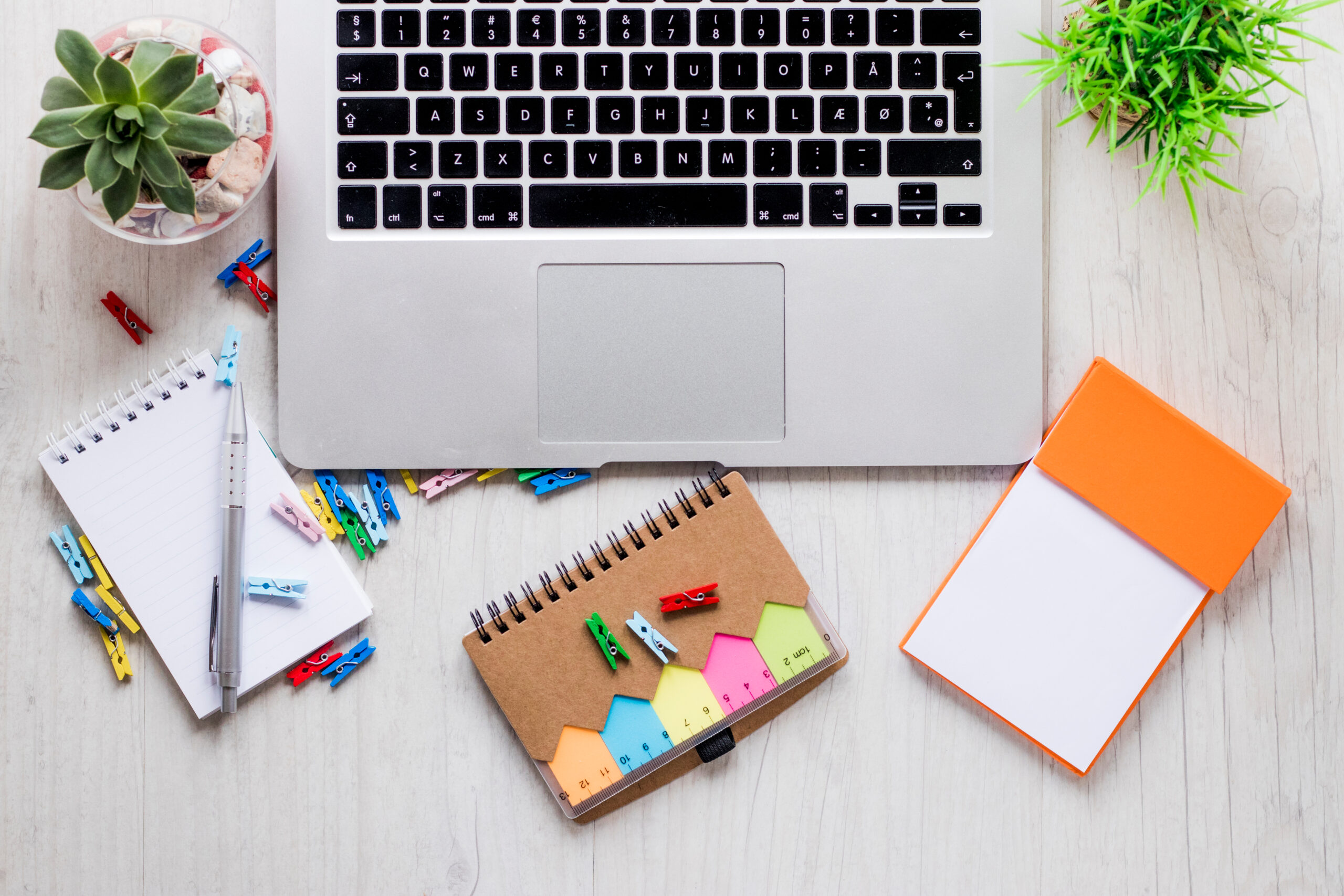 A laptop, notepad, pen, and various office supplies arranged neatly on a clean white table, ready for work.