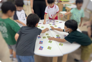 Kids engaged in a fun card game at a table, sharing laughter and excitement in a lively atmosphere.