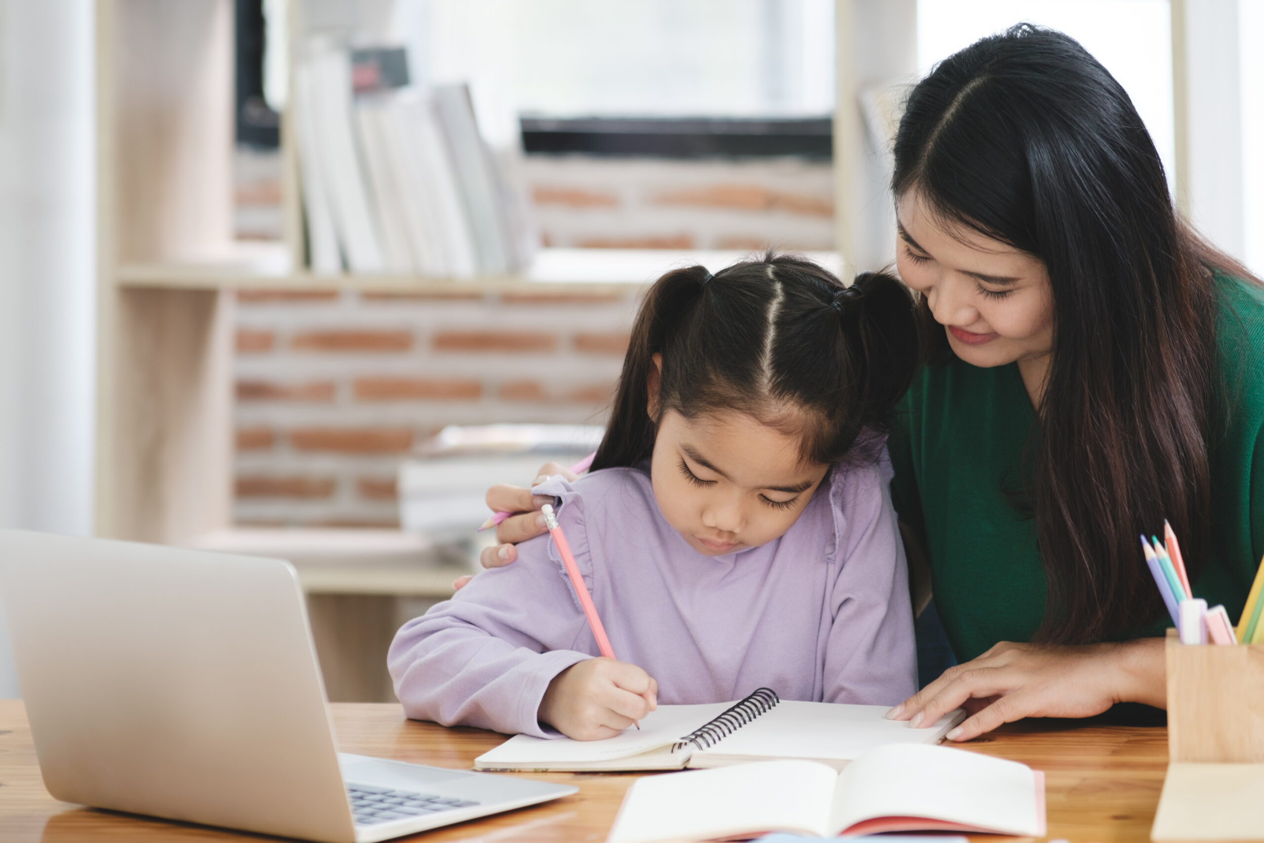 A woman and a child sit side by side,both immersed in their work, showcasing a moment of learning and connection.