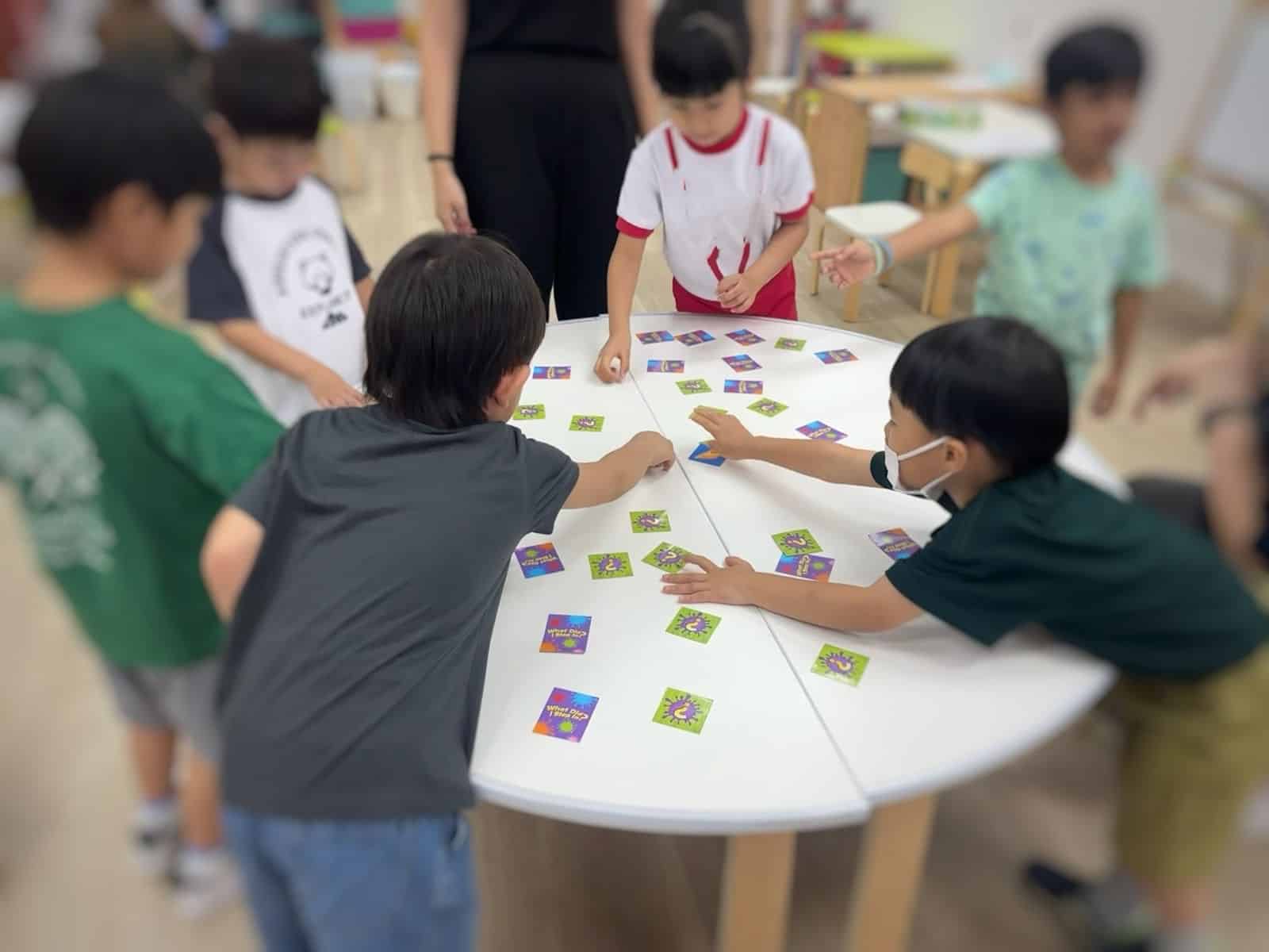 Kids engaged in a fun card game at a table, sharing laughter and excitement in a lively atmosphere.