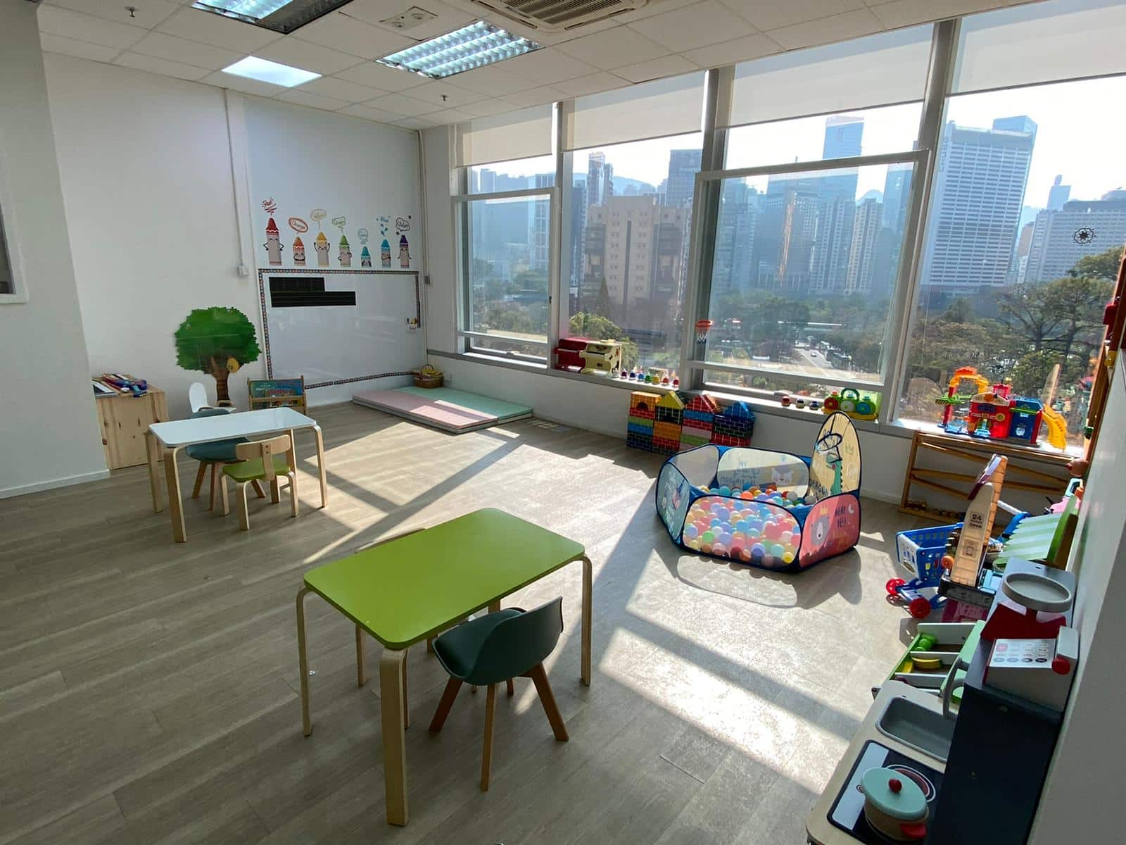 A colorful playroom showcasing an array of toys and chairs, illuminated by sunlight streaming through large windows.